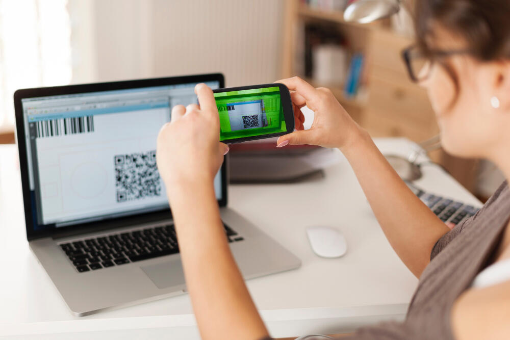 A women scanning a QR code off a computer screen